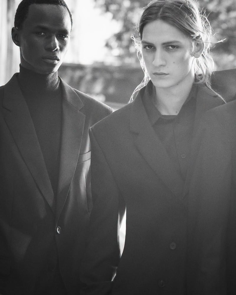 Black-and-white photo of Malick Bodian in a blazer over a turtleneck beside Jesse Rinderknecht in an oversized jacket, for COS's fall 2026 campaign