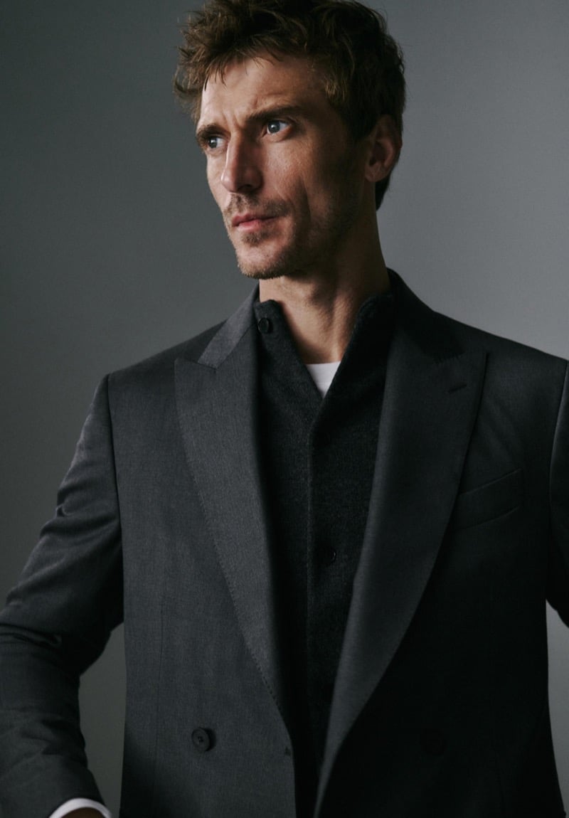 Close portrait of Clément Chabernaud in a charcoal peak-lapel double-breasted jacket layered over a wool overshirt and white tee, looking to the side