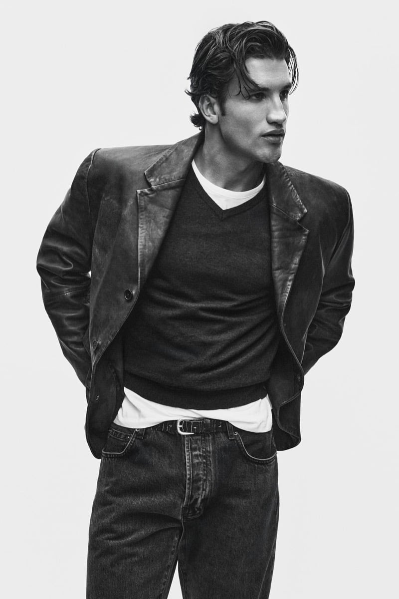 Max Knott in a leather blazer layered over a v-neck sweater and white tee with jeans for Zara's 90's Archive