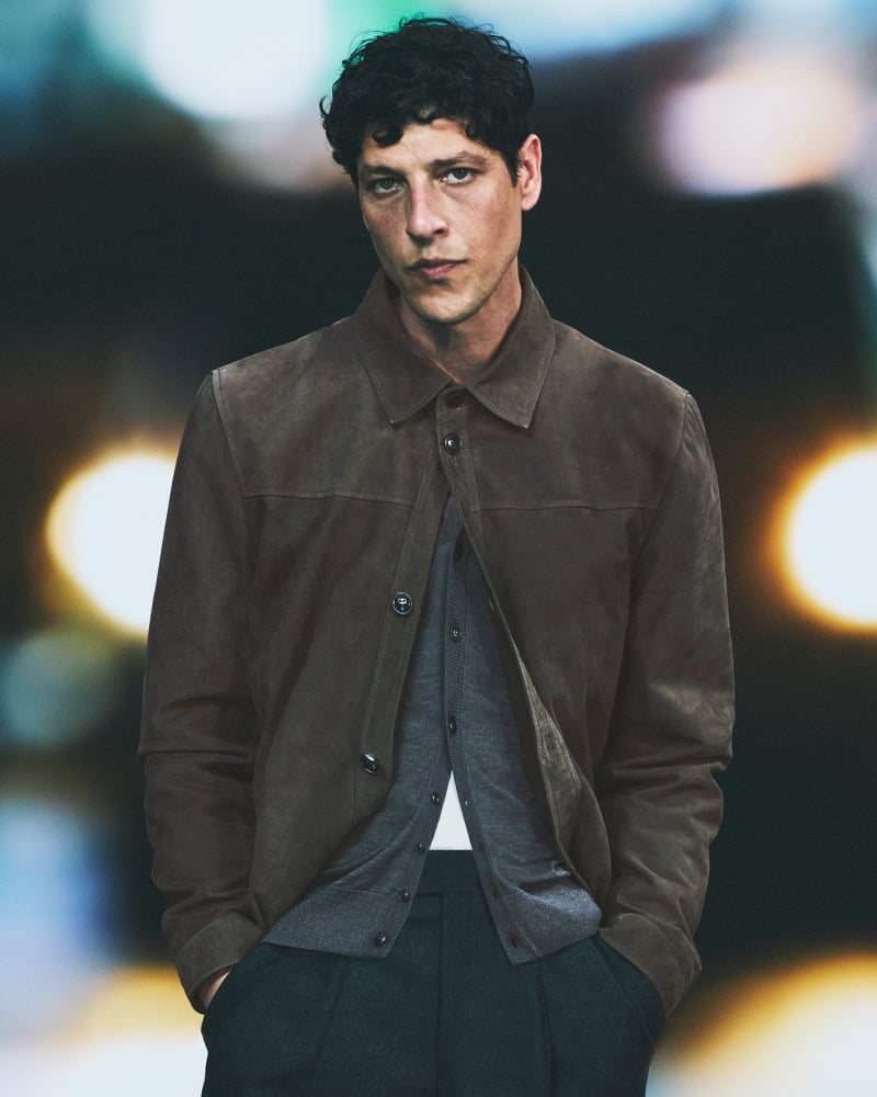 Itshak Vanunu wears a brown suede shirt jacket over a gray cardigan on a nighttime city street for Pal Zileri's fall-winter 2026 campaign.