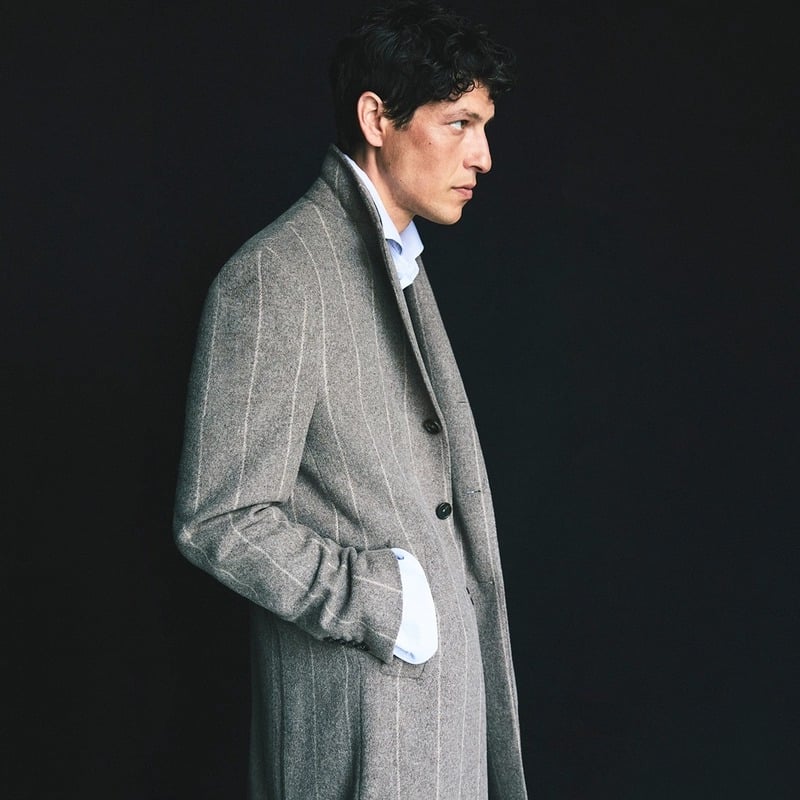 Itshak Vanunu stands in profile wearing a gray pinstriped wool overcoat for Pal Zileri's fall-winter 2026 campaign.