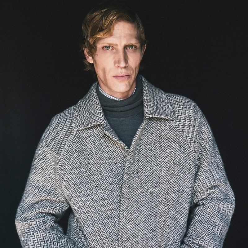 Mike Vasilakis wears a gray herringbone coat over a dark turtleneck for Pal Zileri's fall-winter 2026 campaign.