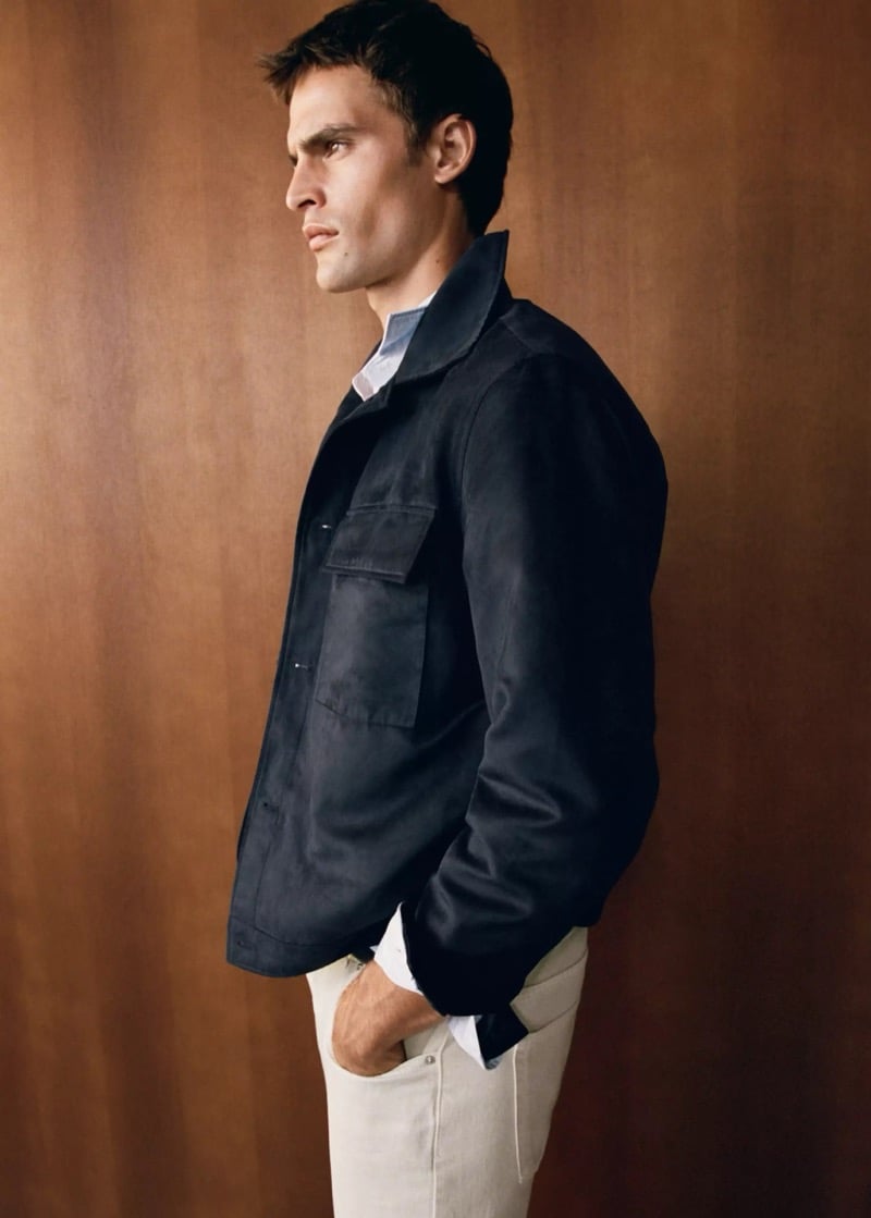 Parker van Noord in profile in a dark suede-effect jacket with chest pockets over a pale shirt and light chinos