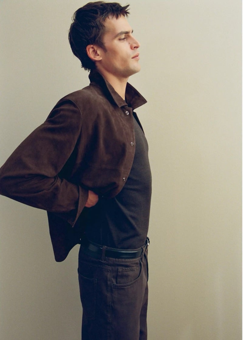 Parker van Noord in profile in a brown suede shirt jacket with snap buttons, a dark tee, and brown jeans
