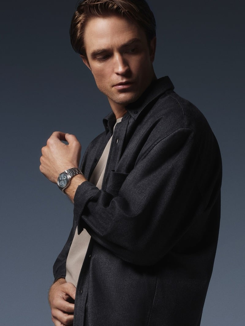 Robert Pattinson glancing down over his shoulder, raising his wrist to show a Jaeger-LeCoultre perpetual calendar watch