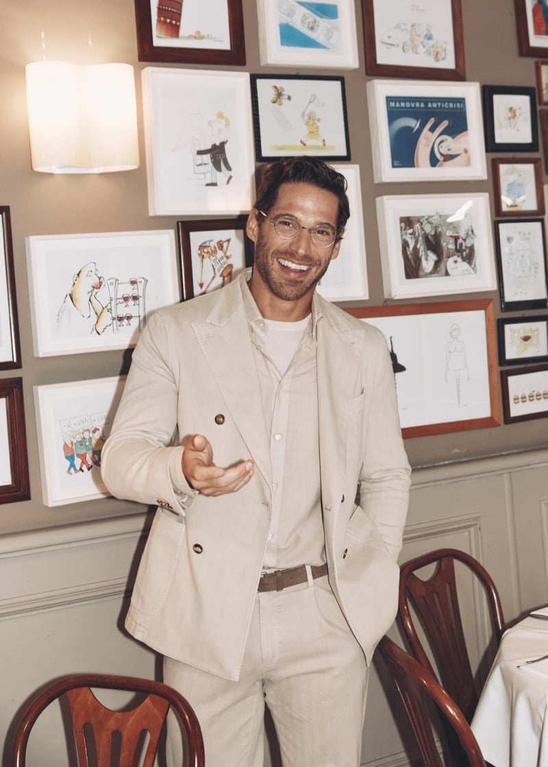 Simone Bredariol laughing in a pale double-breasted suit over an open shirt in a Milan restaurant, for Boglioli's fall-winter 2026 campaign