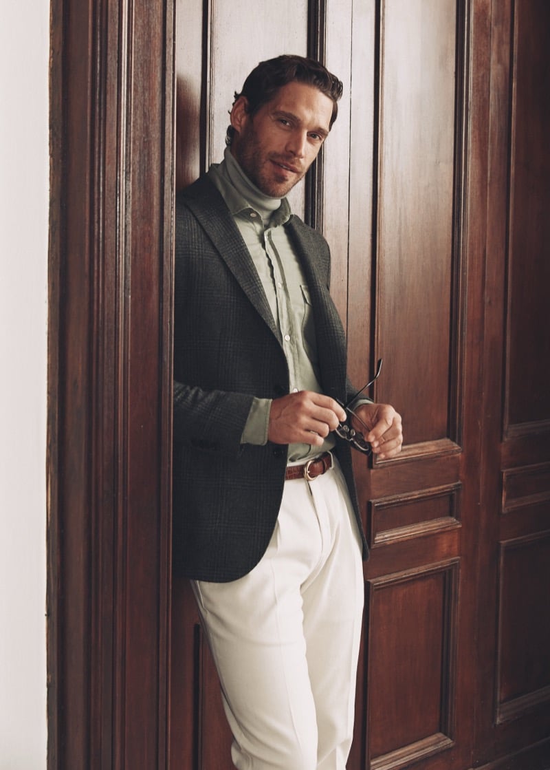 Simone Bredariol against wood-paneled doors in a green checked blazer over a sage shirt with pale trousers, for Boglioli's fall-winter 2026 campaign
