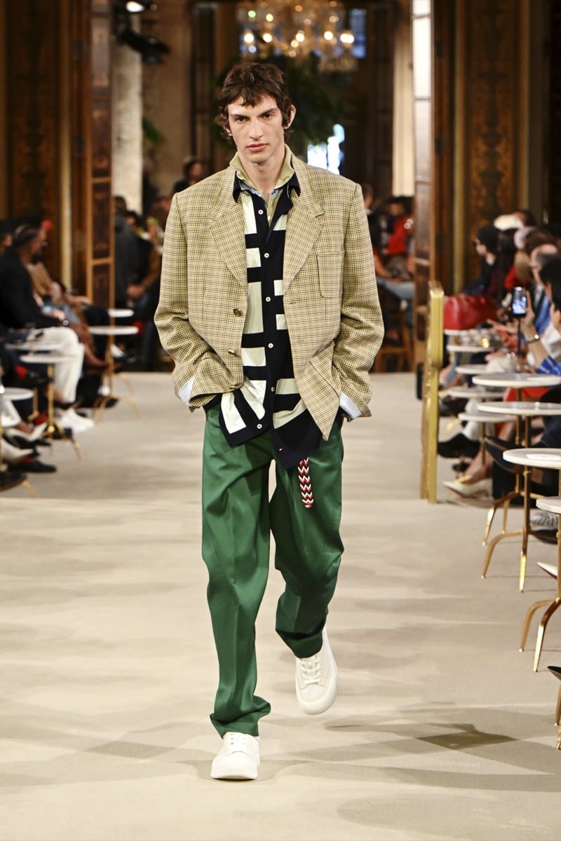 A model in a tan checked blazer over a striped polo, with green wide-leg trousers, for Tommy Hilfiger's spring 2027 collection