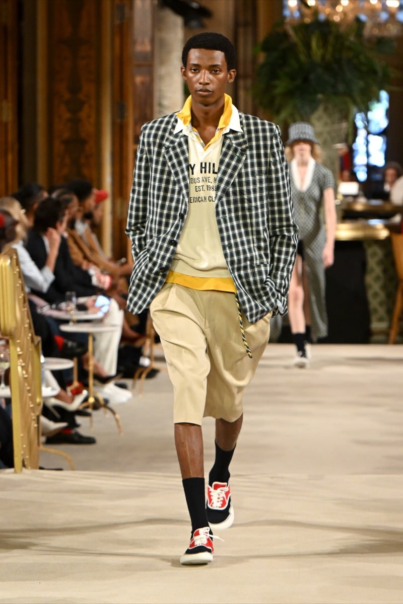 A model in a checked oversized blazer over a yellow graphic polo, with khaki shorts and red sneakers, for Tommy Hilfiger's spring 2027 collection