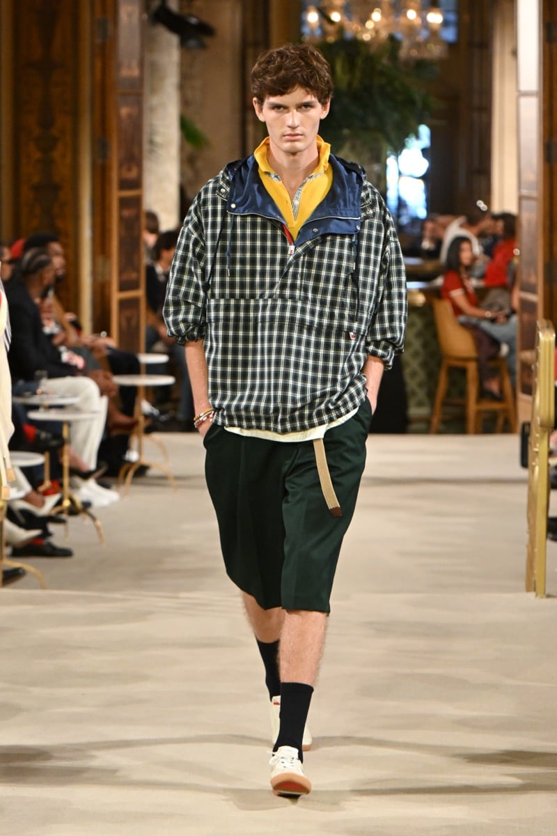 A model in a colorblock hooded anorak with a plaid body over a yellow polo, paired with dark green shorts, for Tommy Hilfiger's spring 2027 collection