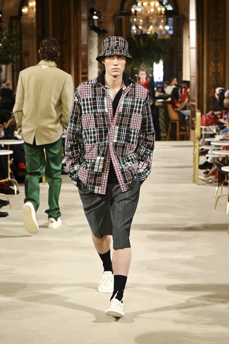 A model in a plaid bucket hat and patchwork plaid overshirt, with pinstripe shorts and white sneakers, for Tommy Hilfiger's spring 2027 collection