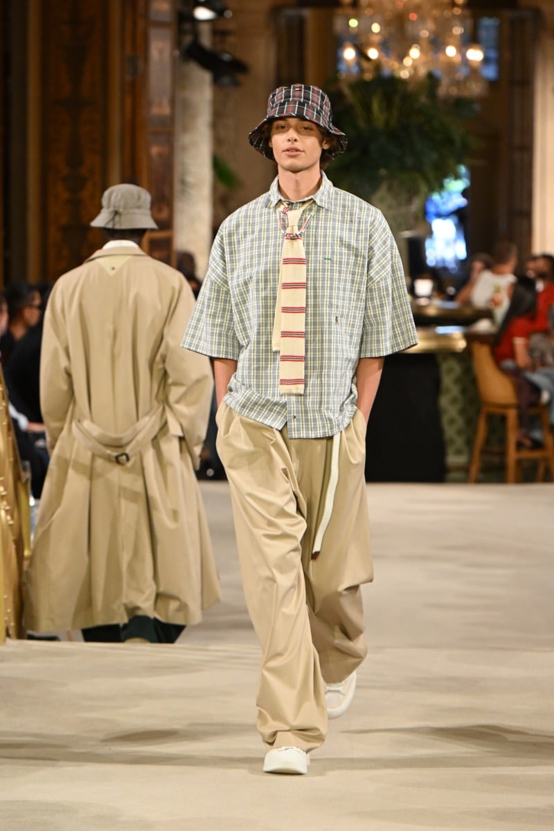 A model in a plaid bucket hat and plaid shirt with a striped tie and khaki wide-leg trousers, for Tommy Hilfiger's spring 2027 collection