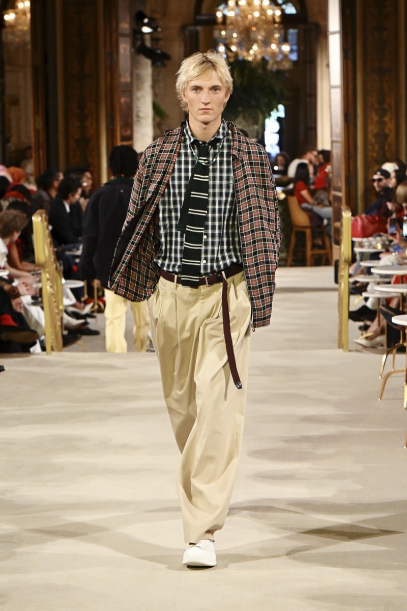 A model in a tartan plaid jacket over a checked shirt and striped tie, with khaki wide-leg trousers, for Tommy Hilfiger's spring 2027 collection