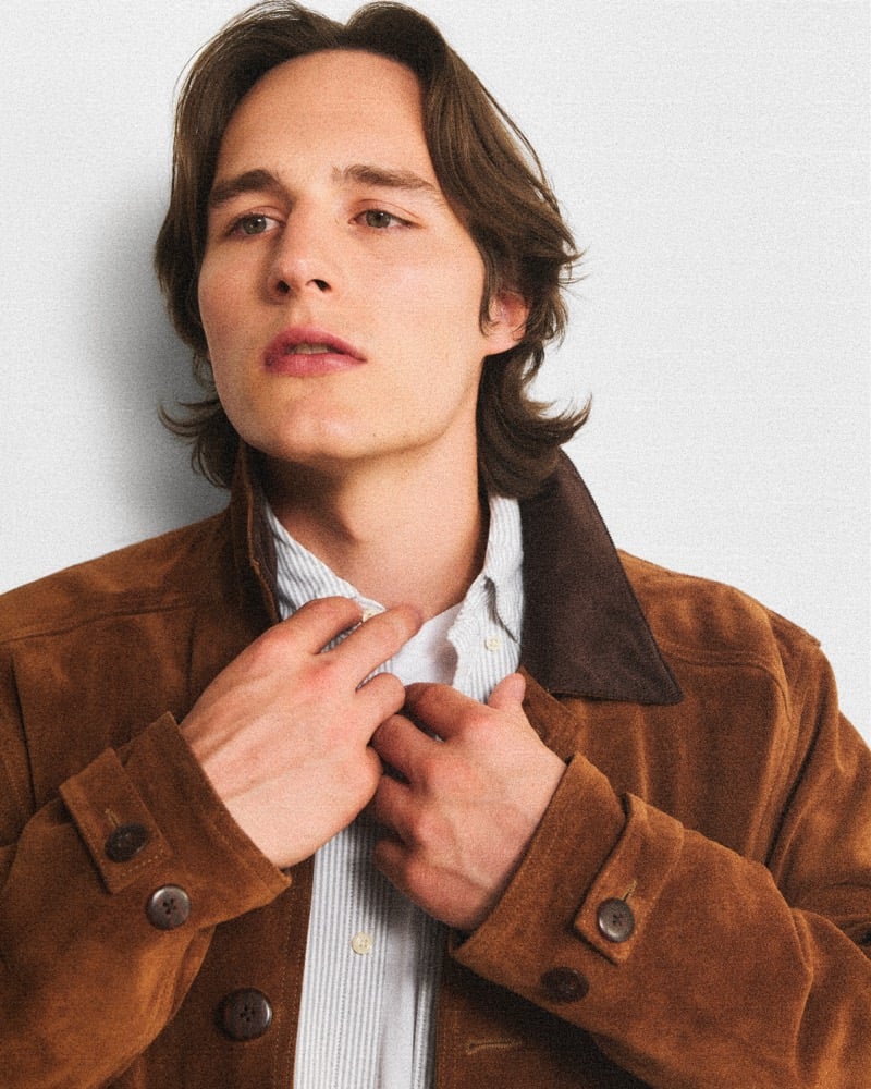Tyler Kolek adjusts the collar of a striped shirt under a brown suede J.Crew jacket