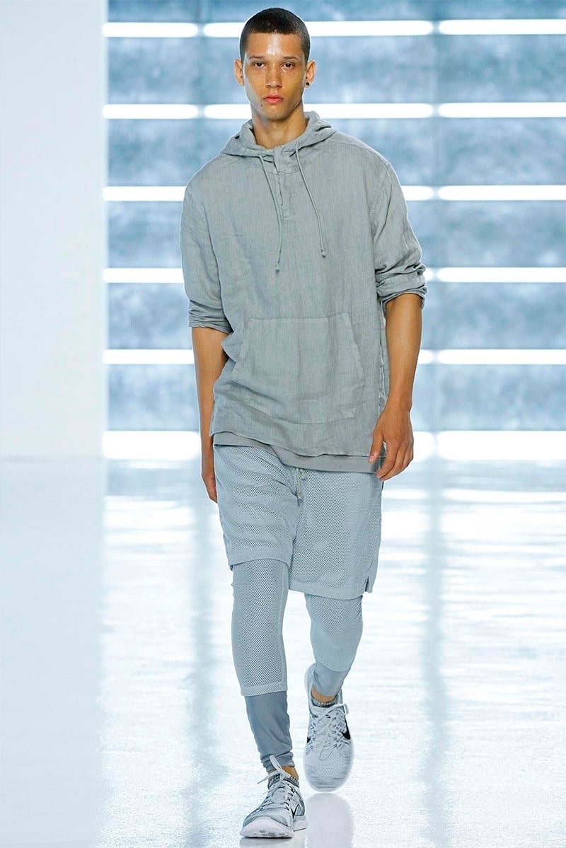 John Elliott spring 2016 runway look with a gray hoodie, shorts over leggings and white sneakers.