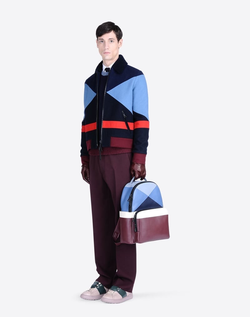 Nicolas Ripoll wears Valentino fall 2015 geometric blue and red outerwear with a coordinated backpack.