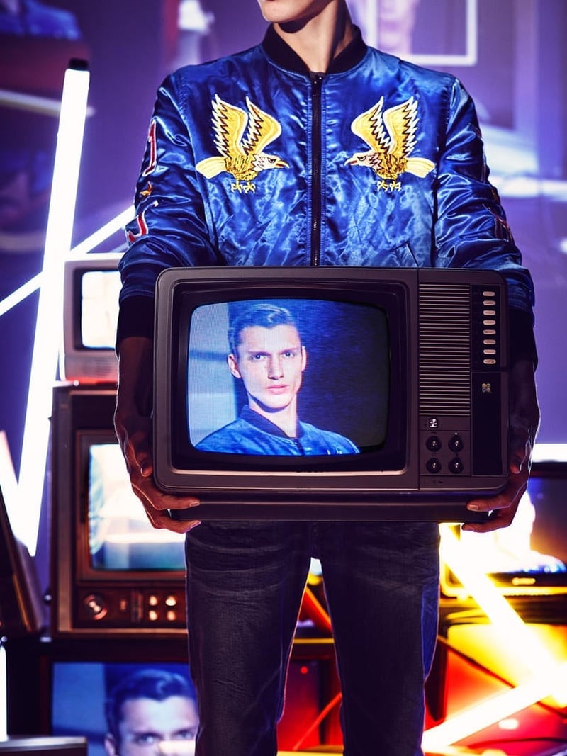 Luca Stascheit wears a blue Diesel souvenir jacket embroidered with yellow eagles in a 2016 Harrods editorial.