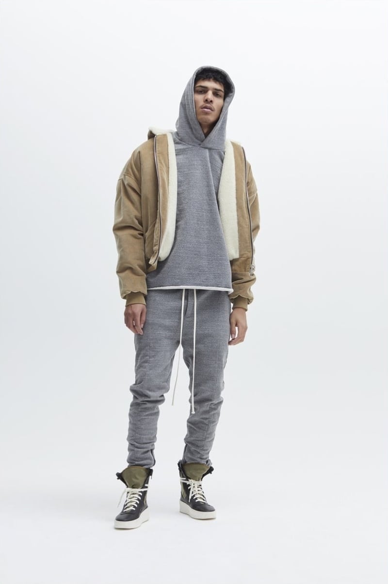 Geron McKinley wears a gray hoodie and joggers beneath a tan hooded jacket with high-top sneakers for Fear of God fall 2017.