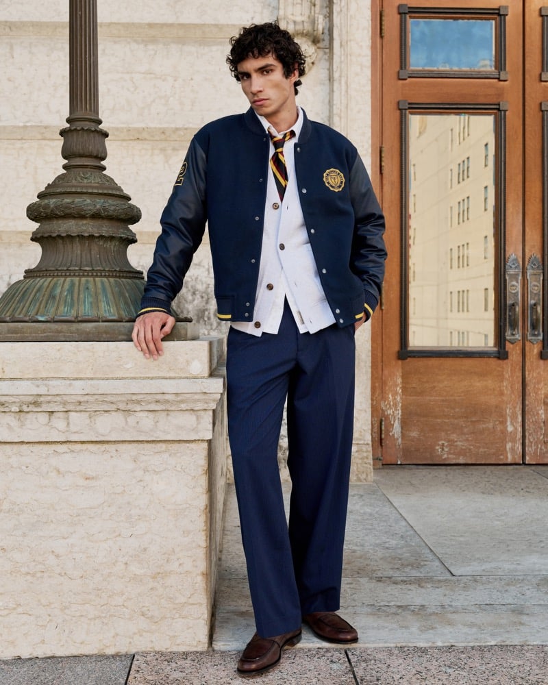 Duncan Yair styles Abercrombie & Fitch’s menswear baggy trouser in navy pinstripe with a varsity jacket, cardigan, and striped tie.