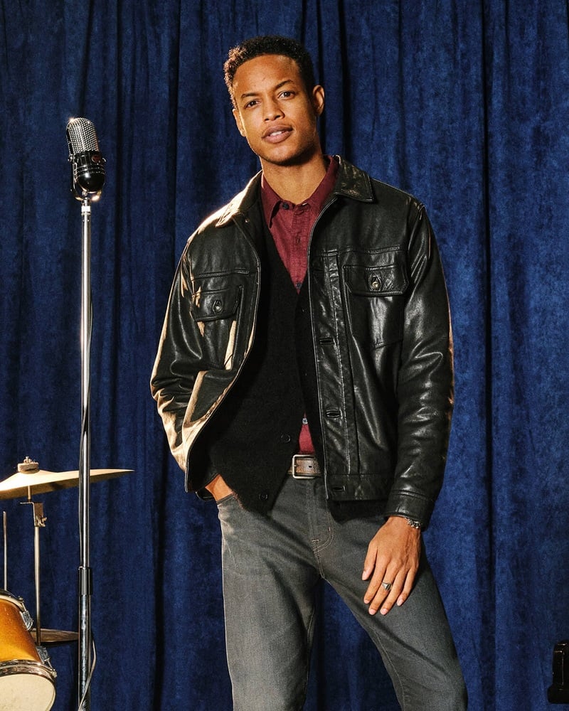 Conrad Bromfield wears a black leather jacket over a dark knit and burgundy shirt for AG Jeans' fall 2026 Indigo Sessions campaign.