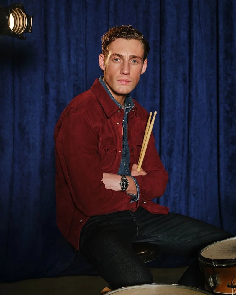 Aubrey O'Mahony holds drumsticks in a red overshirt and denim shirt for AG Jeans' Indigo Sessions campaign.