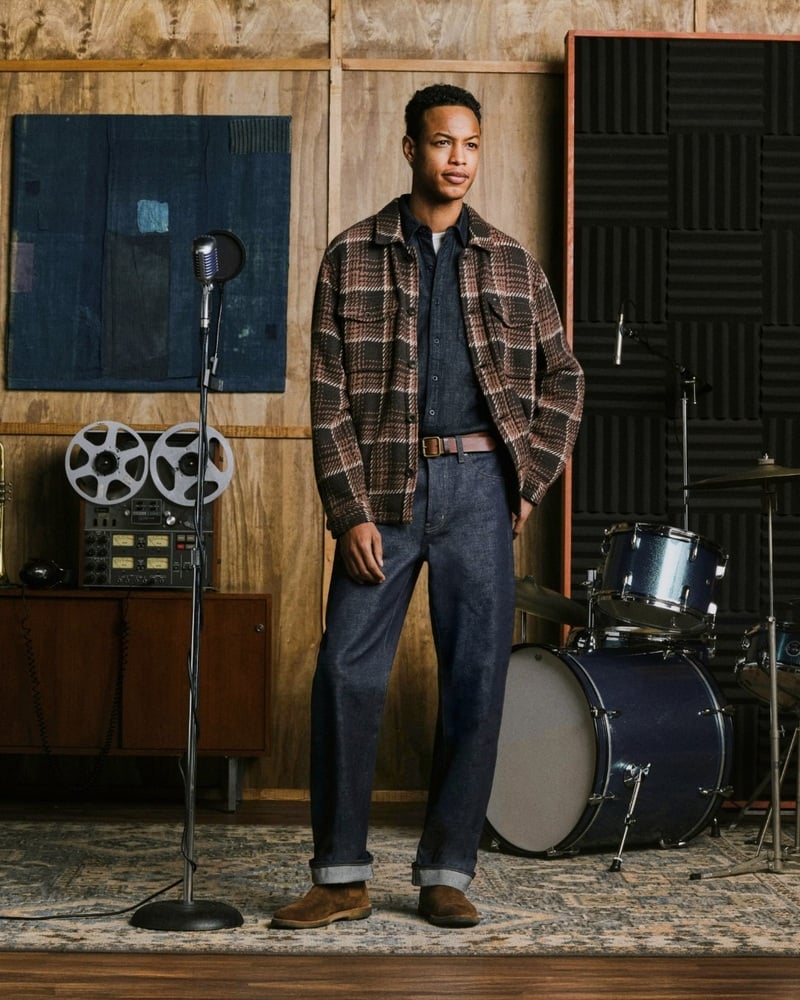 Conrad Bromfield wears a checked jacket with cuffed jeans in a recording studio.