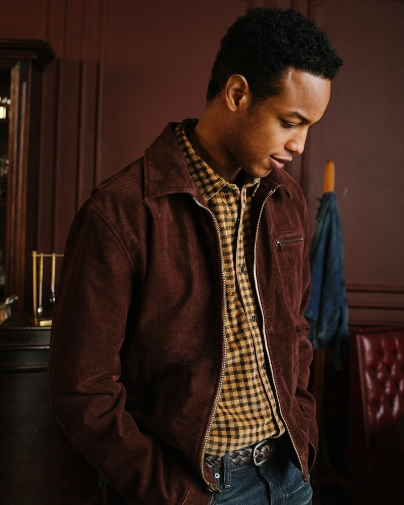 Conrad Bromfield wears a brown jacket over a checked shirt in a bar.