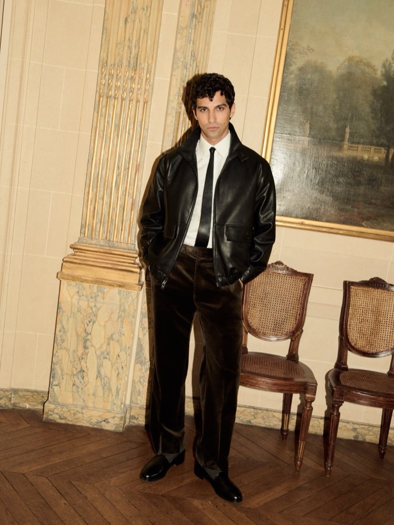 Francisco Faria wears a black leather blouson jacket over a white shirt and dark tie with tailored velvet trousers.