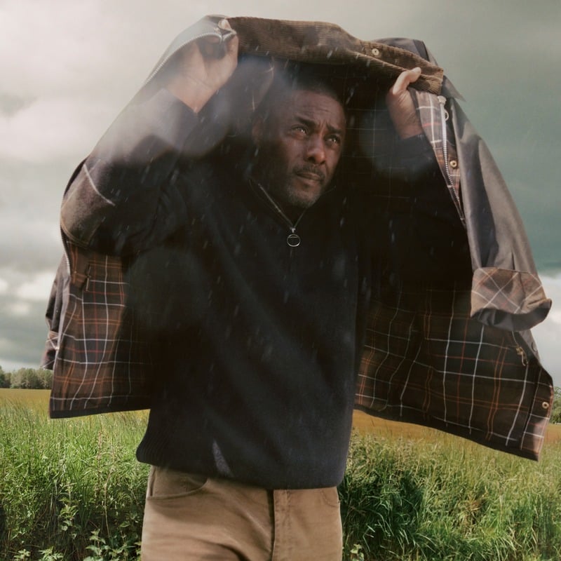 Idris Elba shelters beneath a waxed jacket with tartan lining in Barbour's fall-winter 2026 Original & Authentic Tartans campaign.