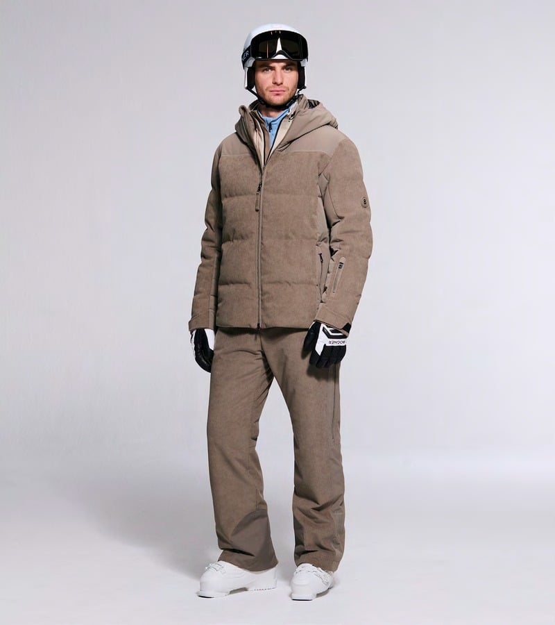A model wears a taupe padded ski jacket and matching trousers with a helmet. Bogner fall-winter 2026 collection.