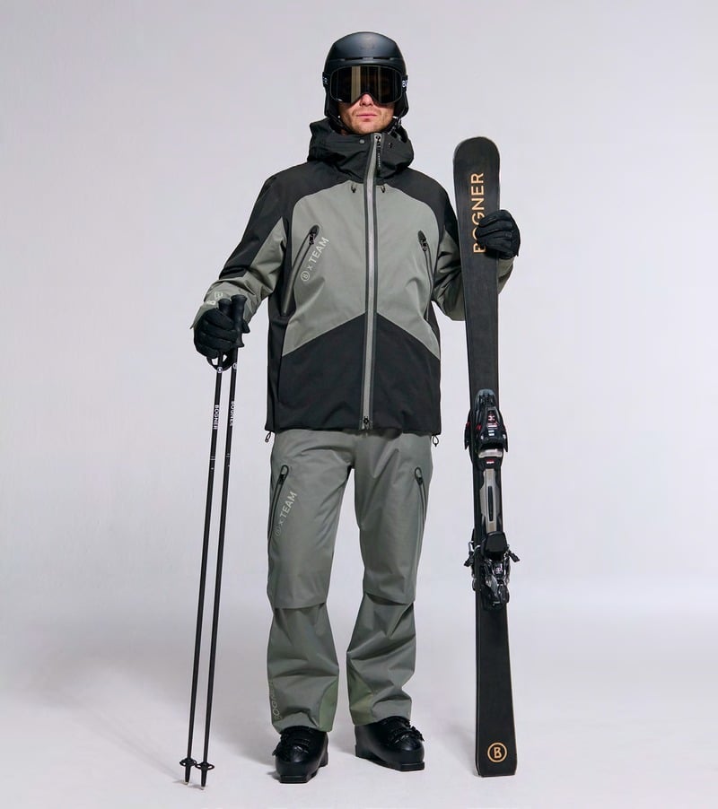A model wears a gray and black ski jacket with gray trousers and holds skis. Bogner fall-winter 2026 collection.