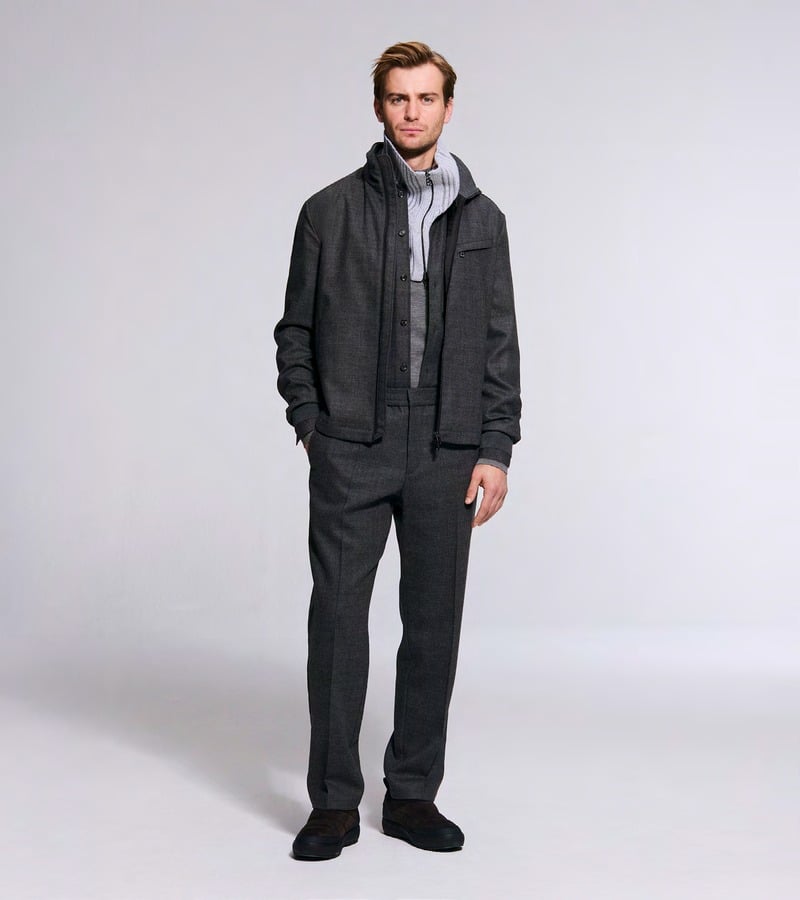 Ben Allen wears a charcoal jacket over a gray hooded layer with dark trousers. Bogner fall-winter 2026 collection.