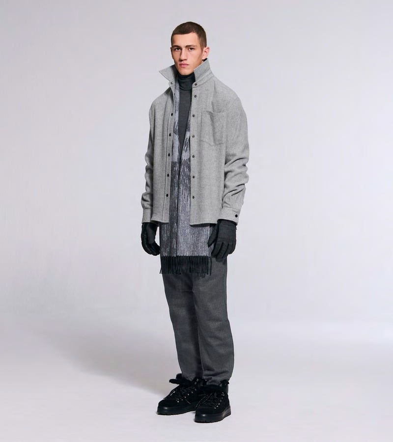 A model wears a light gray overshirt with a patterned scarf and dark trousers. Bogner fall-winter 2026 collection.