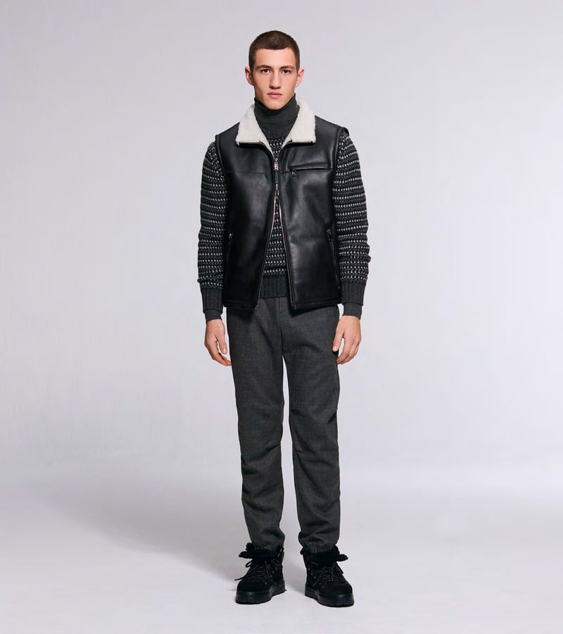 A model wears a black quilted vest over gray knitwear with dark trousers. Bogner fall-winter 2026 collection.