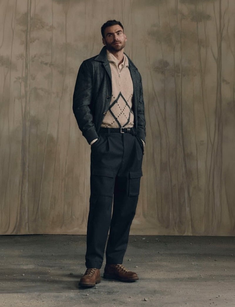 George Alsford in a dark leather jacket, pale diamond-pattern sweater, pleated trousers and brown shoes for Brunello Cucinelli Winter Edit