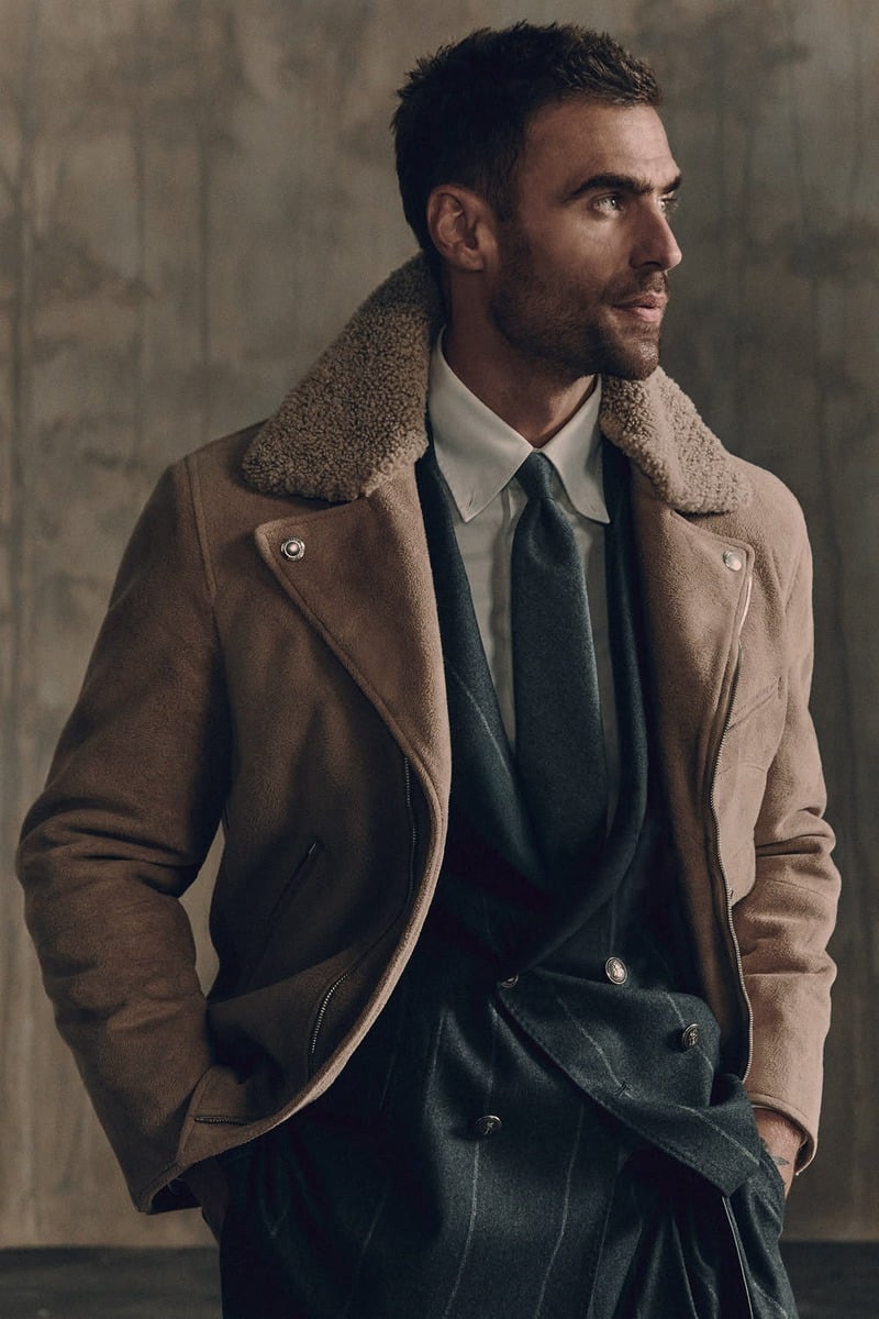 George Alsford in a brown shearling-collar jacket over a pinstriped suit with a white shirt and tie for Brunello Cucinelli Winter Edit