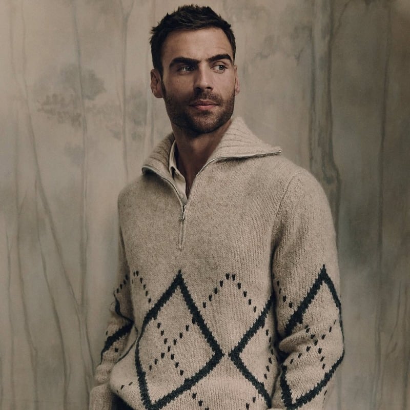 George Alsford wearing a pale zip-neck sweater with dark diamond patterns for Brunello Cucinelli Winter Edit