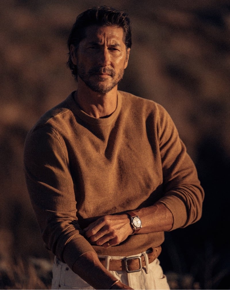 Ryan Porter wears a rust sweater tucked into jeans.