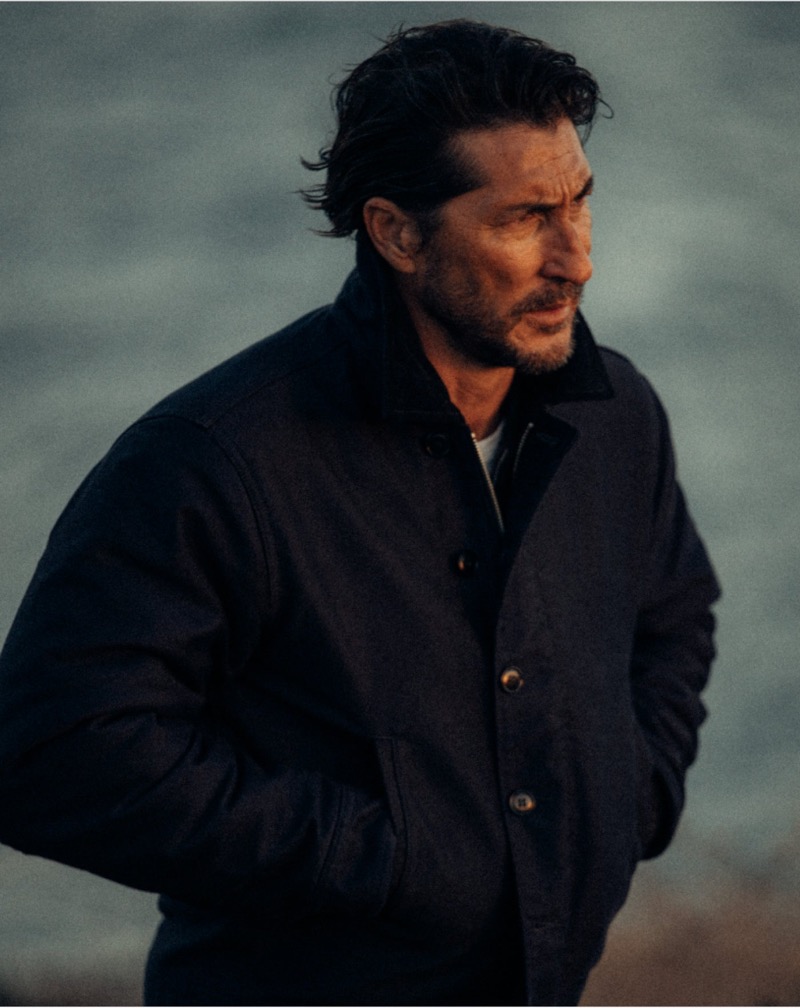 Ryan Porter wears a deck jacket by the sea.