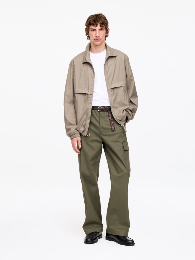 Beige jacket, white T-shirt, olive wide cargo trousers and black loafers from ARKET.