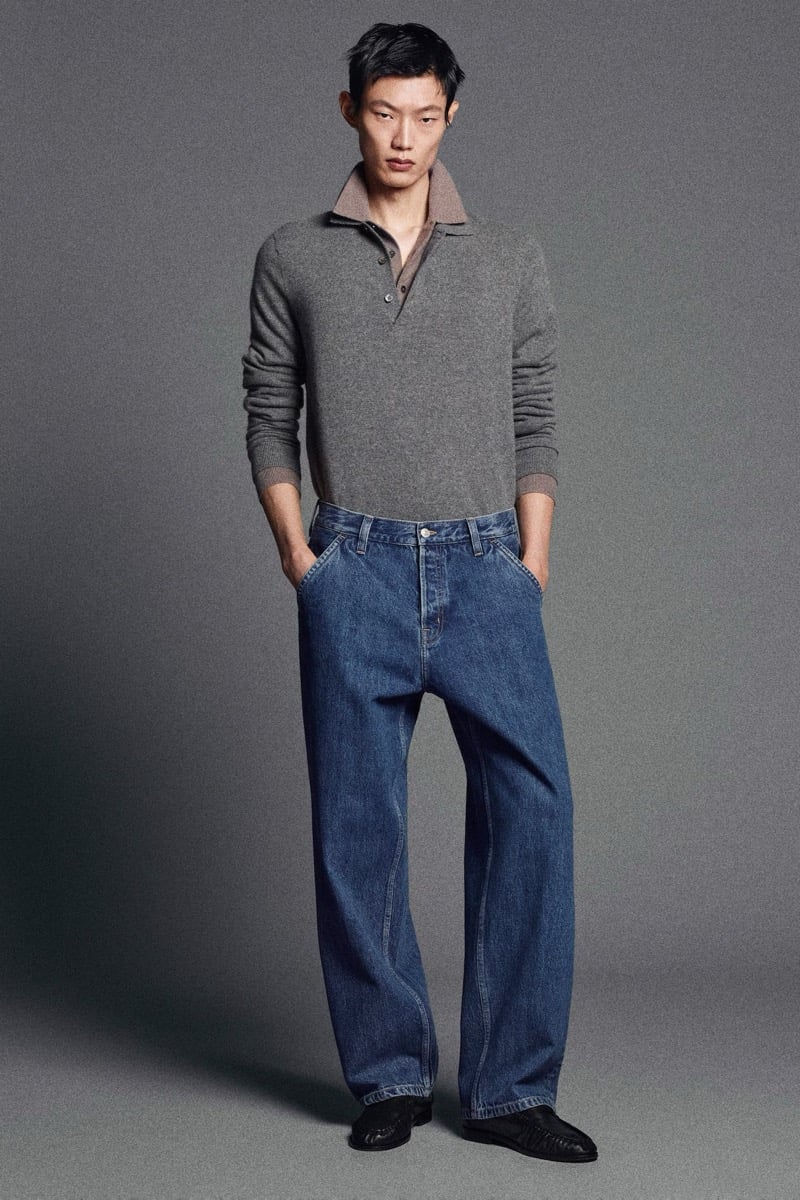 Hoyong Kim wears a gray cashmere polo tucked into wide-leg blue jeans.