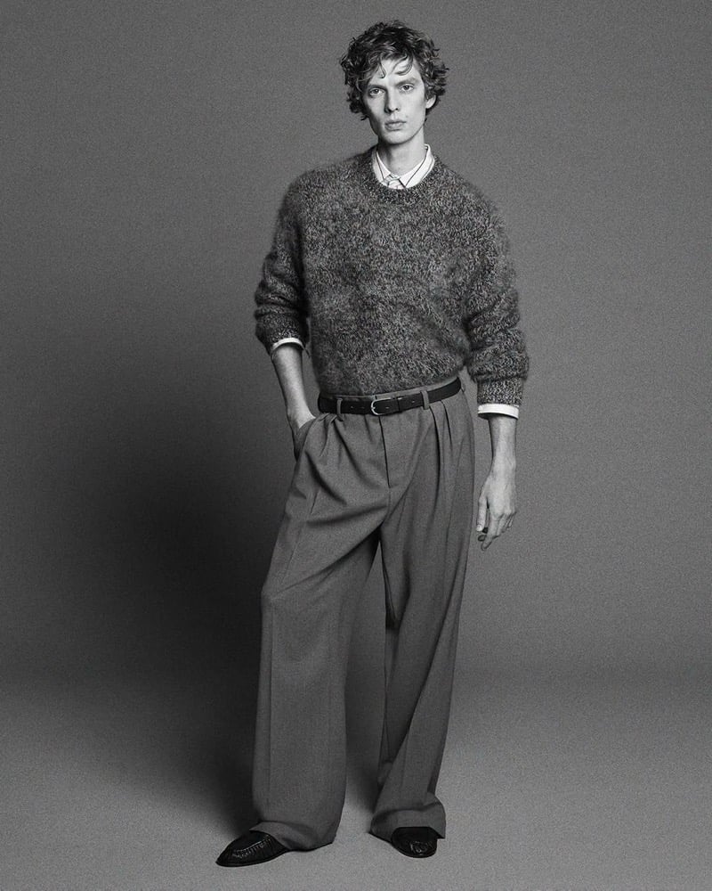 Leon Dame wears a brushed cashmere sweater with a striped shirt and wide-leg pleated trousers.
