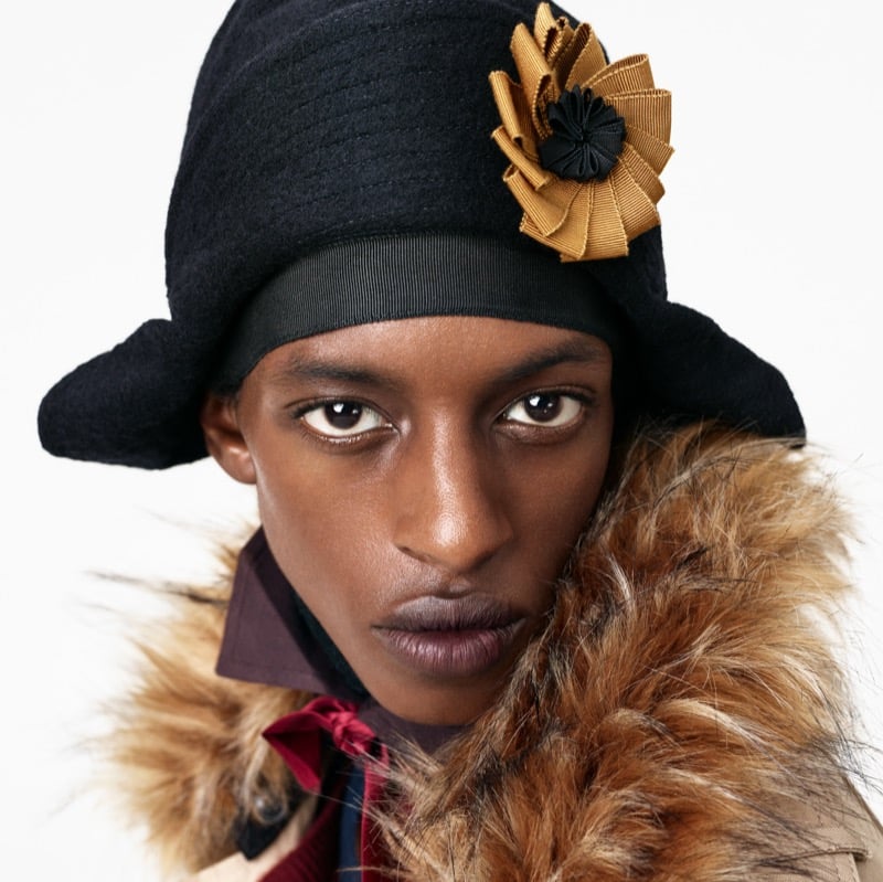 Close-up of Craig Shimirmana in a felt hat with a ribbon rosette and a faux fur collar over a collared shirt and silk scarf