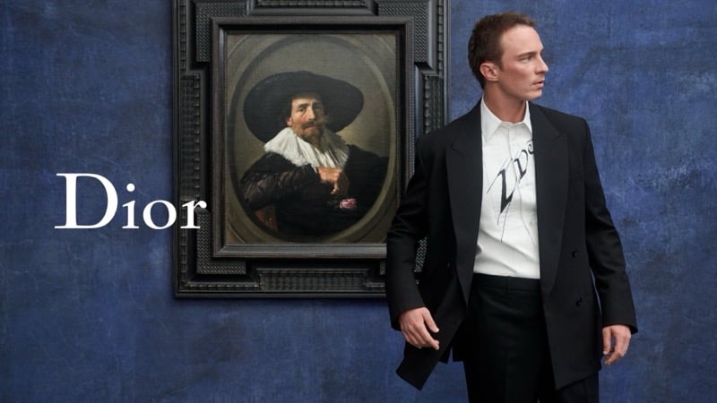 Drew Starkey in a black jacket and trousers with a white printed shirt beside a Frans Hals portrait at LACMA.