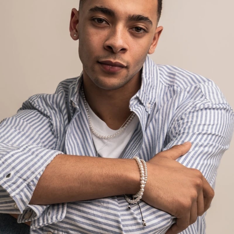 A pearl bracelet from Dower & Hall adds ornament to a striped shirt and white tee.