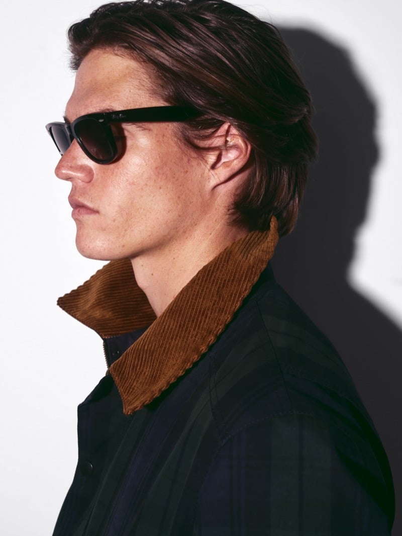 Profile of Drew Carter in sunglasses, a corduroy collar turned up over a Black Watch plaid jacket