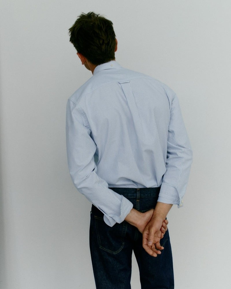 Eddie Klint faces away, showing the back pleat and locker loop of his blue Oxford shirt