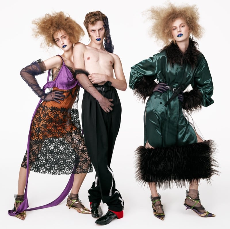 Frauke Nijs in a purple slip over black lace, Wiley Rhoads shirtless in high-waisted pleated trousers, and Julia Nobis in a green satin coat with faux fur cuffs and hem