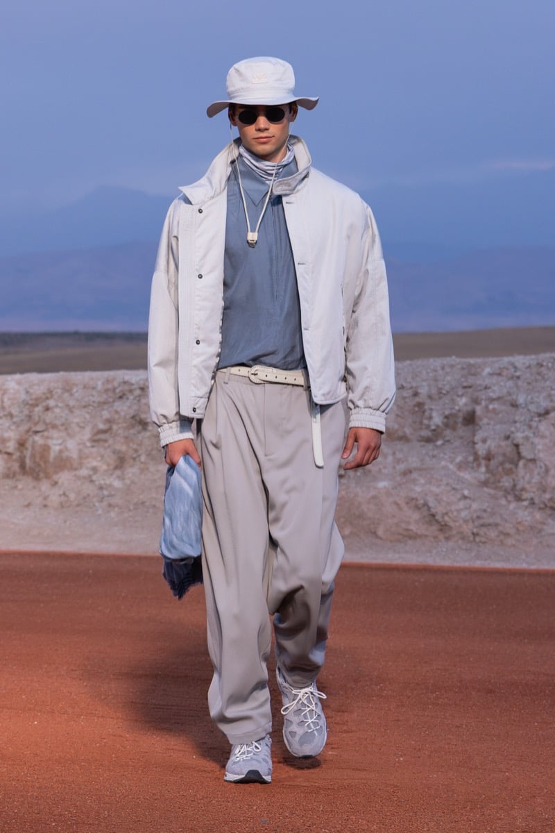 Model wears a pale blue jacket, blue top, loose gray trousers, and a bucket hat at the Giorgio Armani x Kith fall-winter 2026 show.