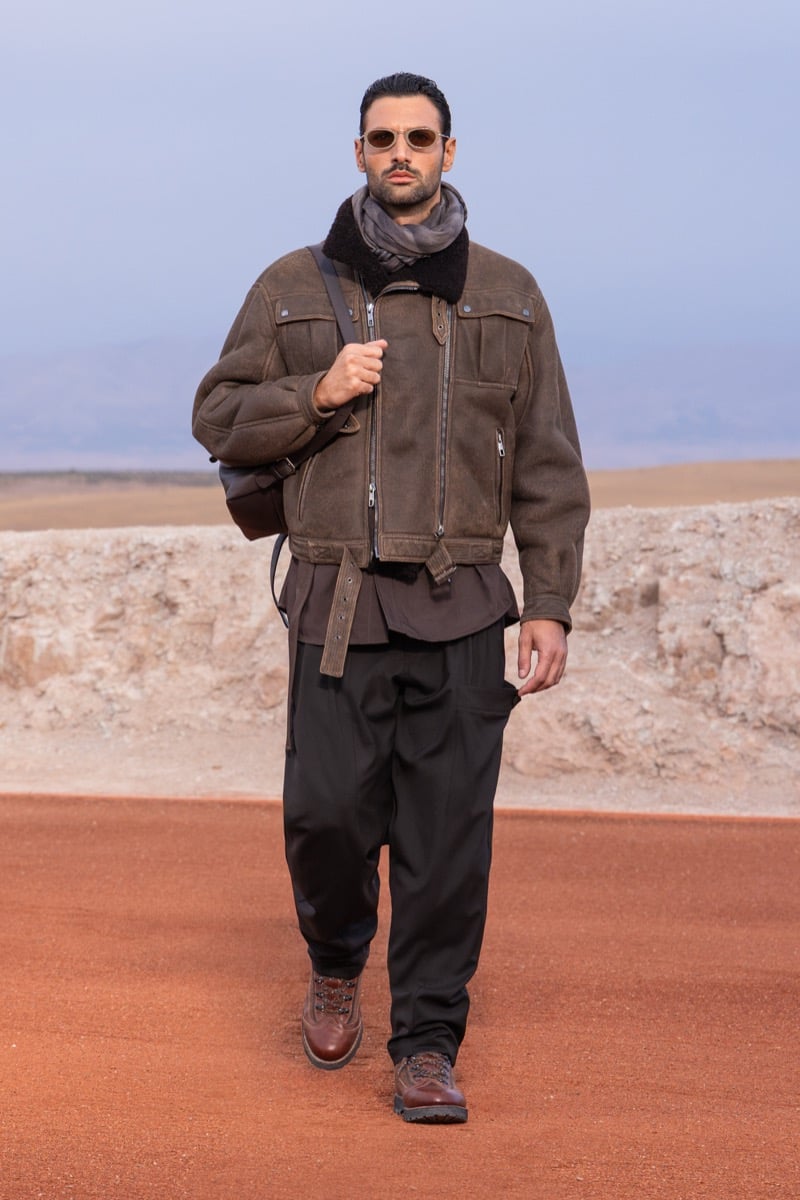 Model wears a brown shearling-trimmed jacket, dark trousers, a scarf, and boots at the Giorgio Armani x Kith fall-winter 2026 show.
